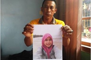 Suharna saat memperlihatkan foto anaknya yang hilang.